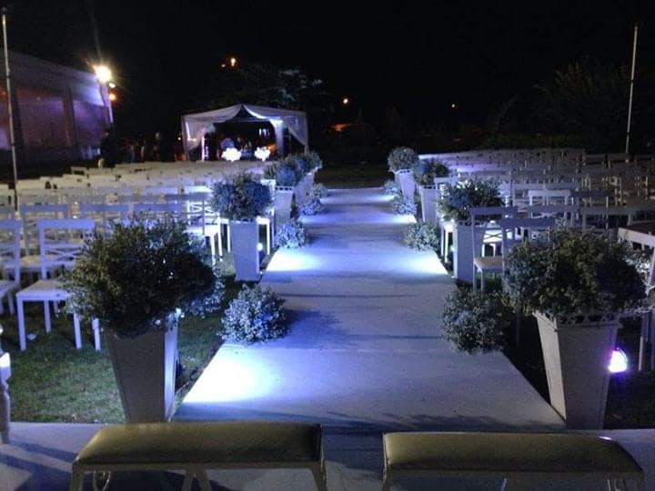 Corredor da cerimônia à noite, com cadeiras brancas e iluminação azul