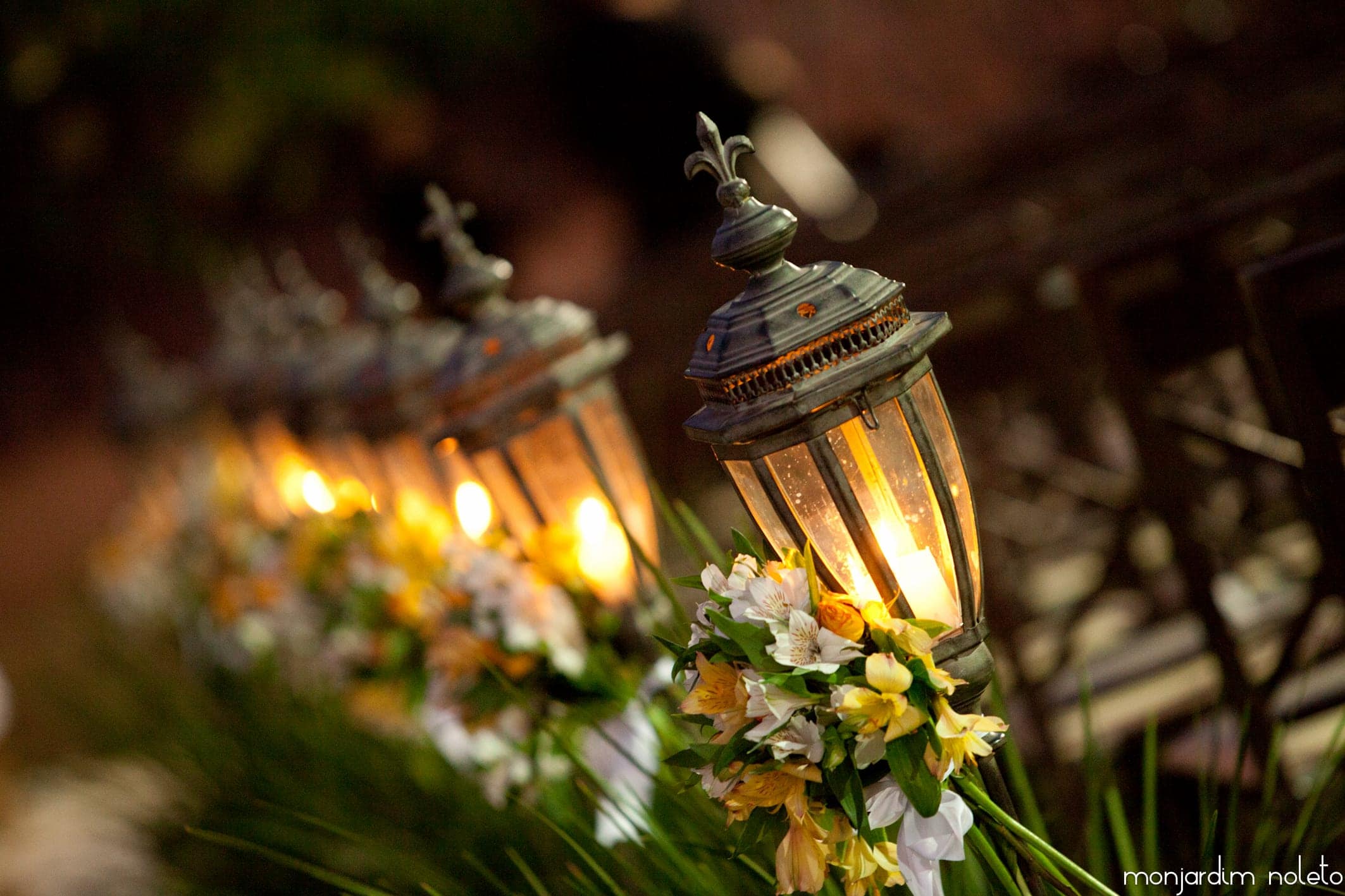 Lanternas acesas entre arranjos de flores brancas