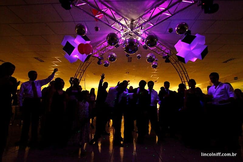 Pista de dança lotada sob luzes roxas e âmbar