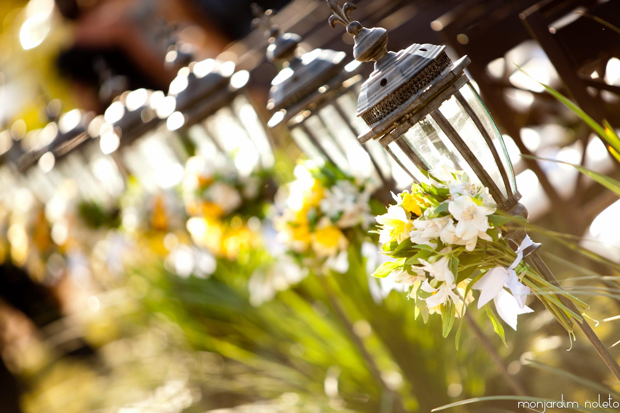 Arranjos de flores amarelas e brancas sobre a mesa, sob a luz do lustre