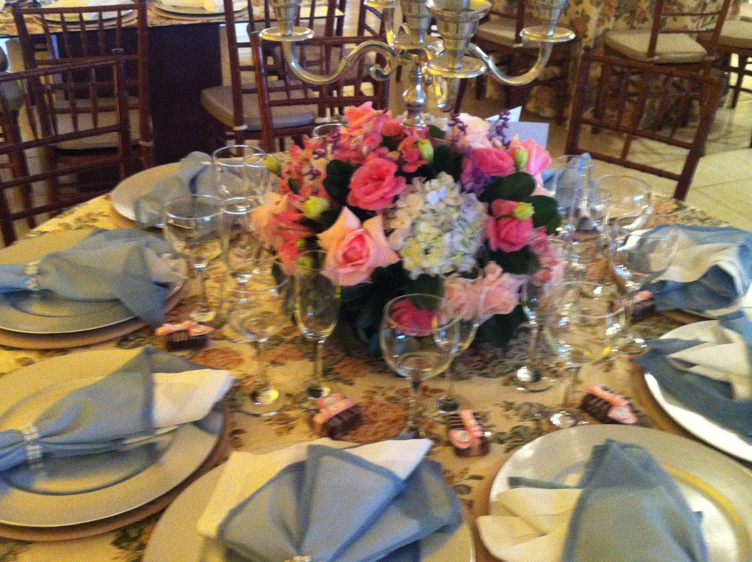 Mesa posta com arranjo de flores rosa e guardanapos dobrados