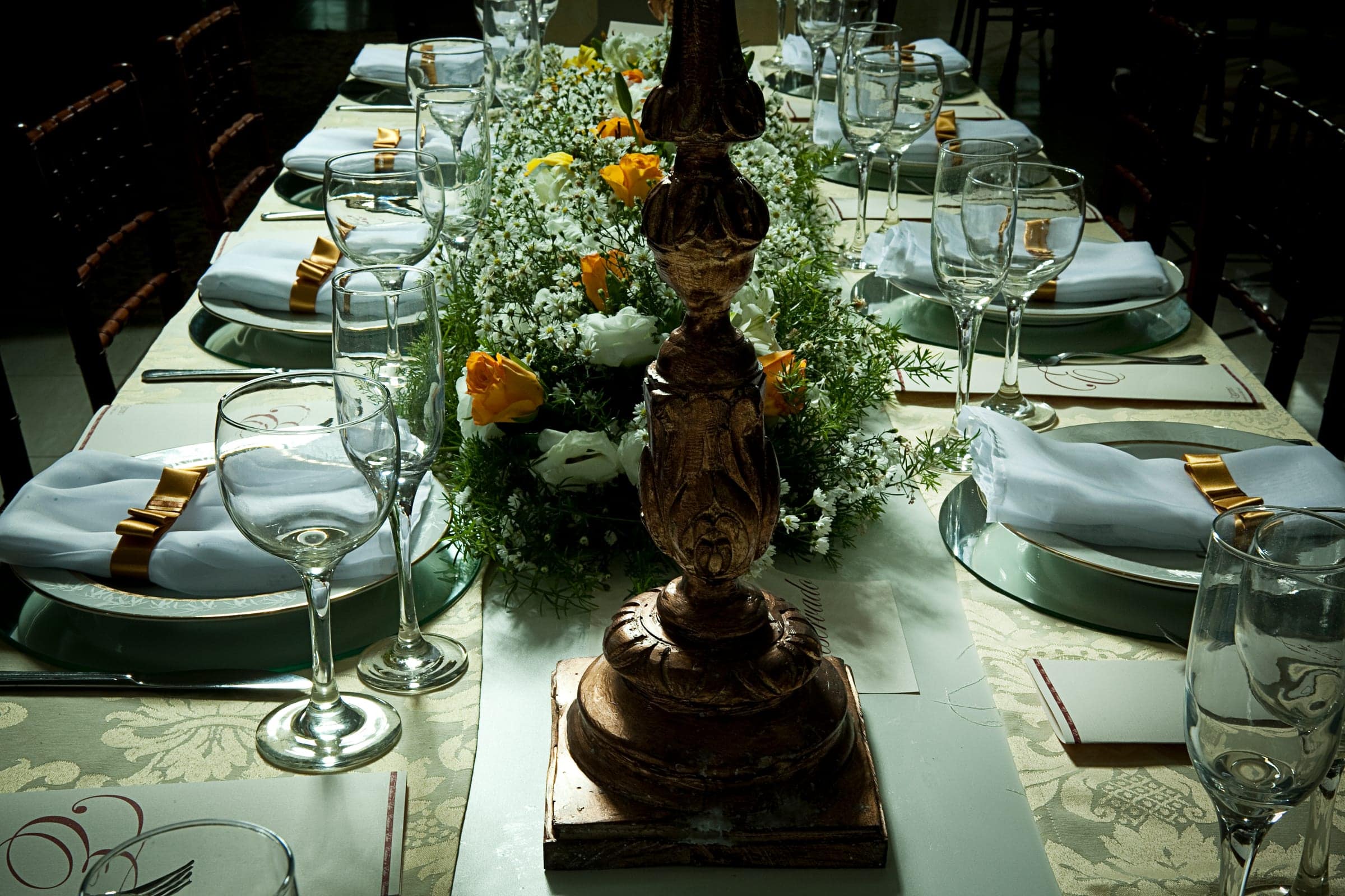Mesa imperial com toalha verde, arranjos ao centro e taças alinhadas