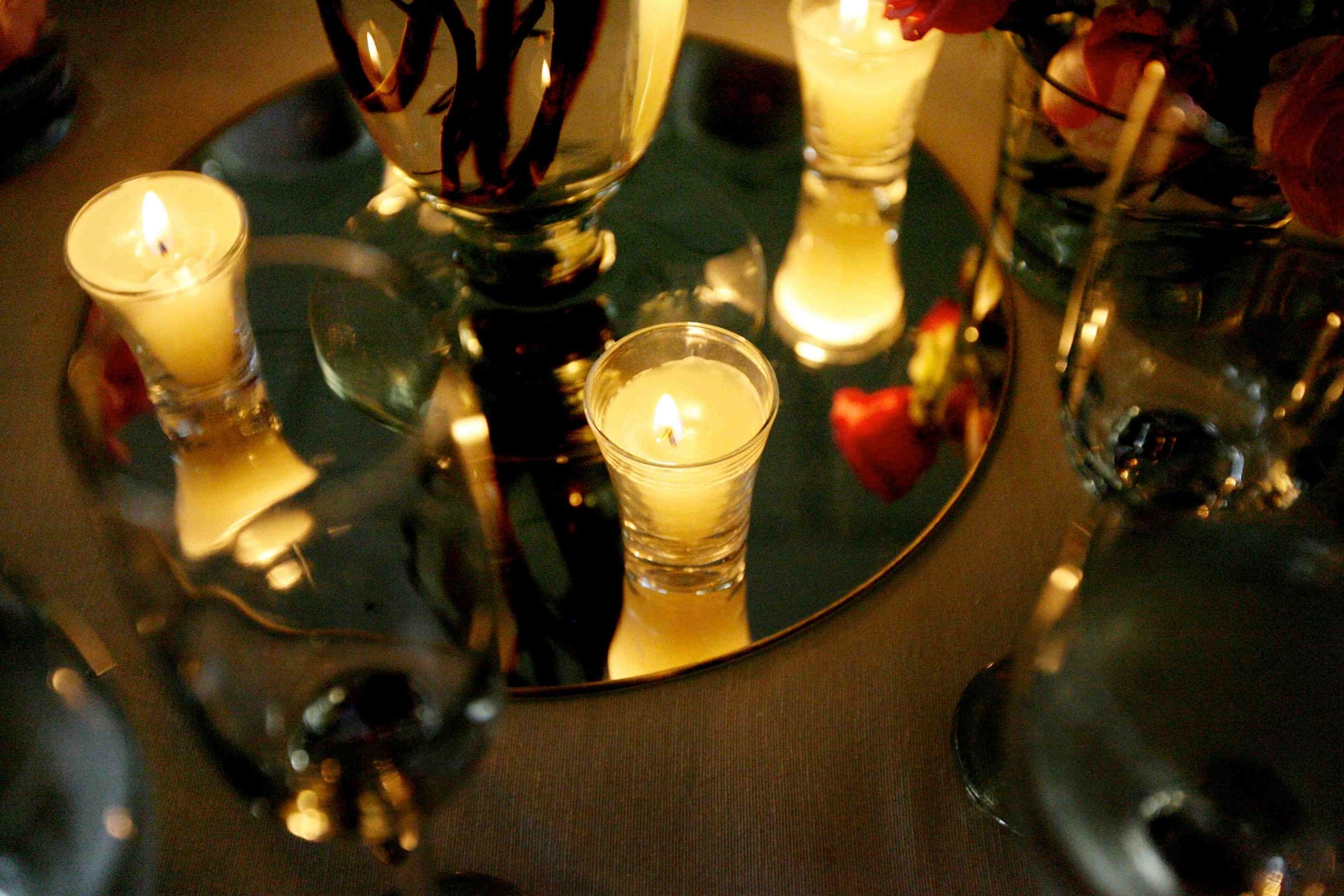 Velas e taças sobre mesa espelhada, em luz dourada