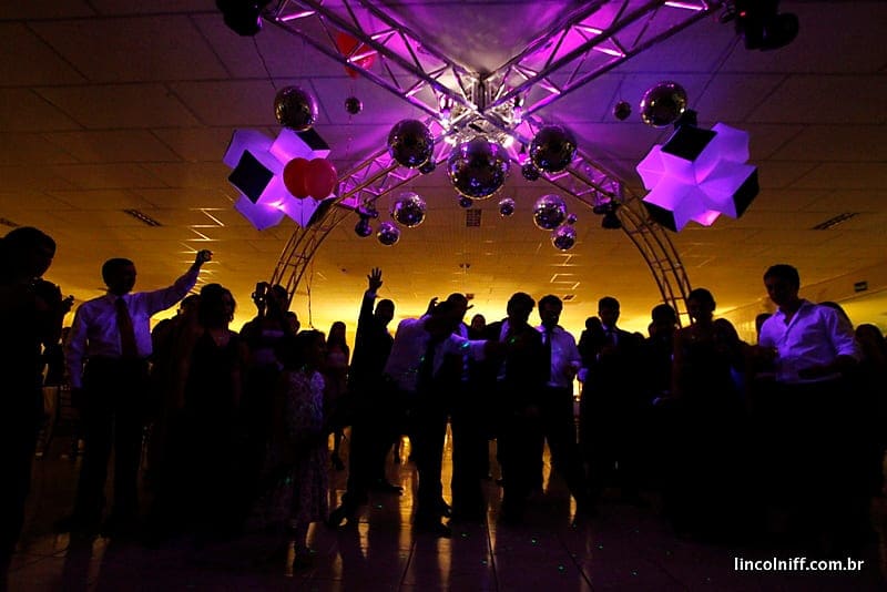Pista de dança lotada sob luzes roxas e âmbar