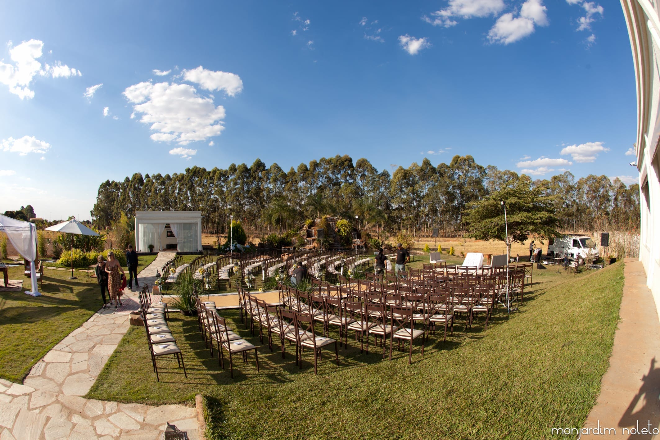 Cadeiras alinhadas no gramado para cerimônia ao ar livre, sob céu aberto